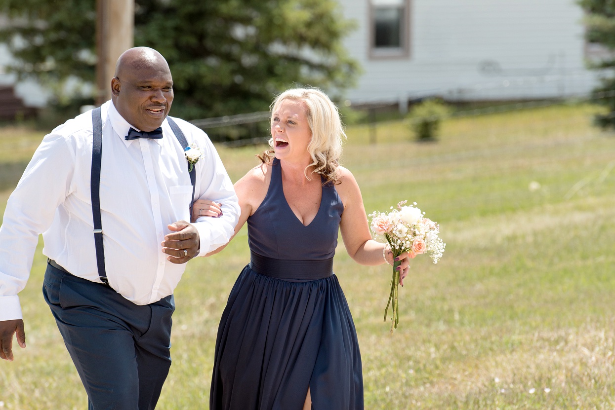 Bridesmaid and groomsmen walking down aisle, laughing wedding party