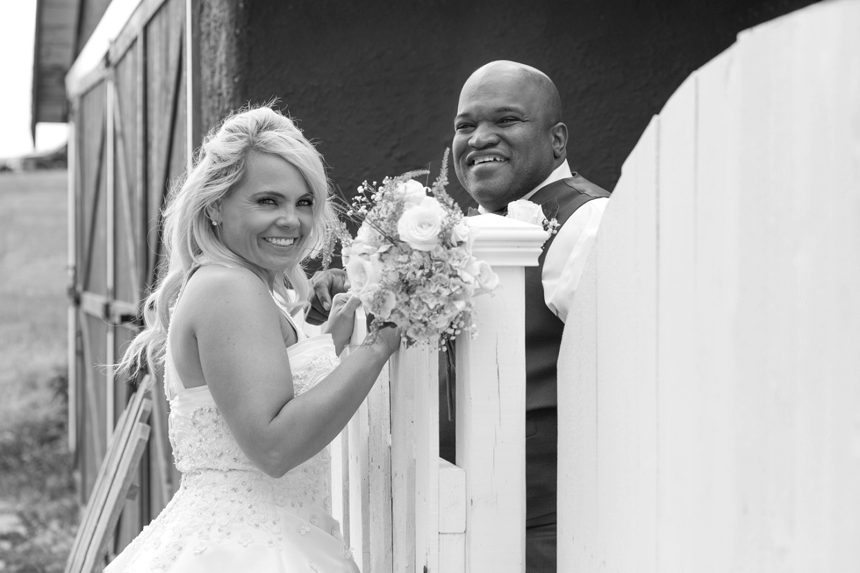 Bride and groom on either side of a fence